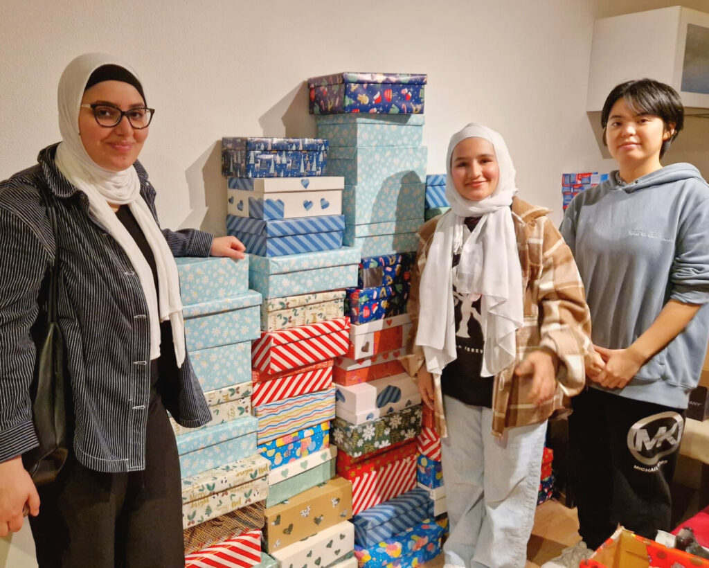 Three students standing together with wrapped shoeboxes